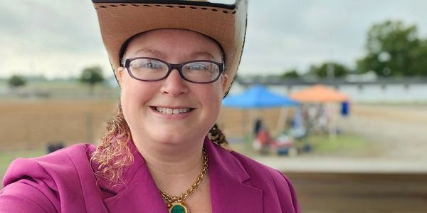 Smiling woman in a cowboy hat and glasses.