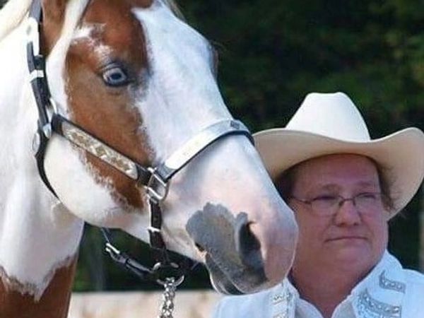 Man in cowboy hat and a horse with blue eye.