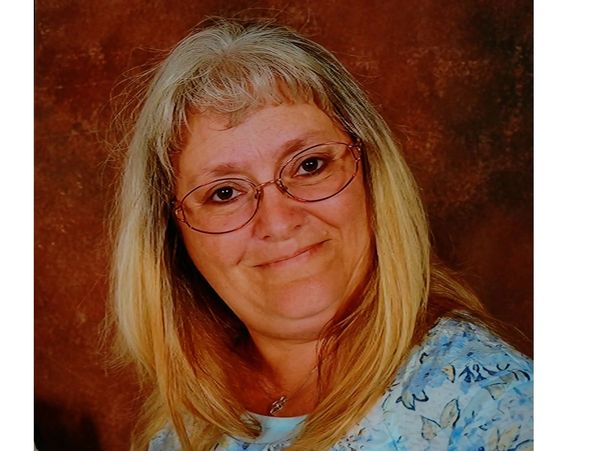 Smiling woman with glasses and blonde hair.
