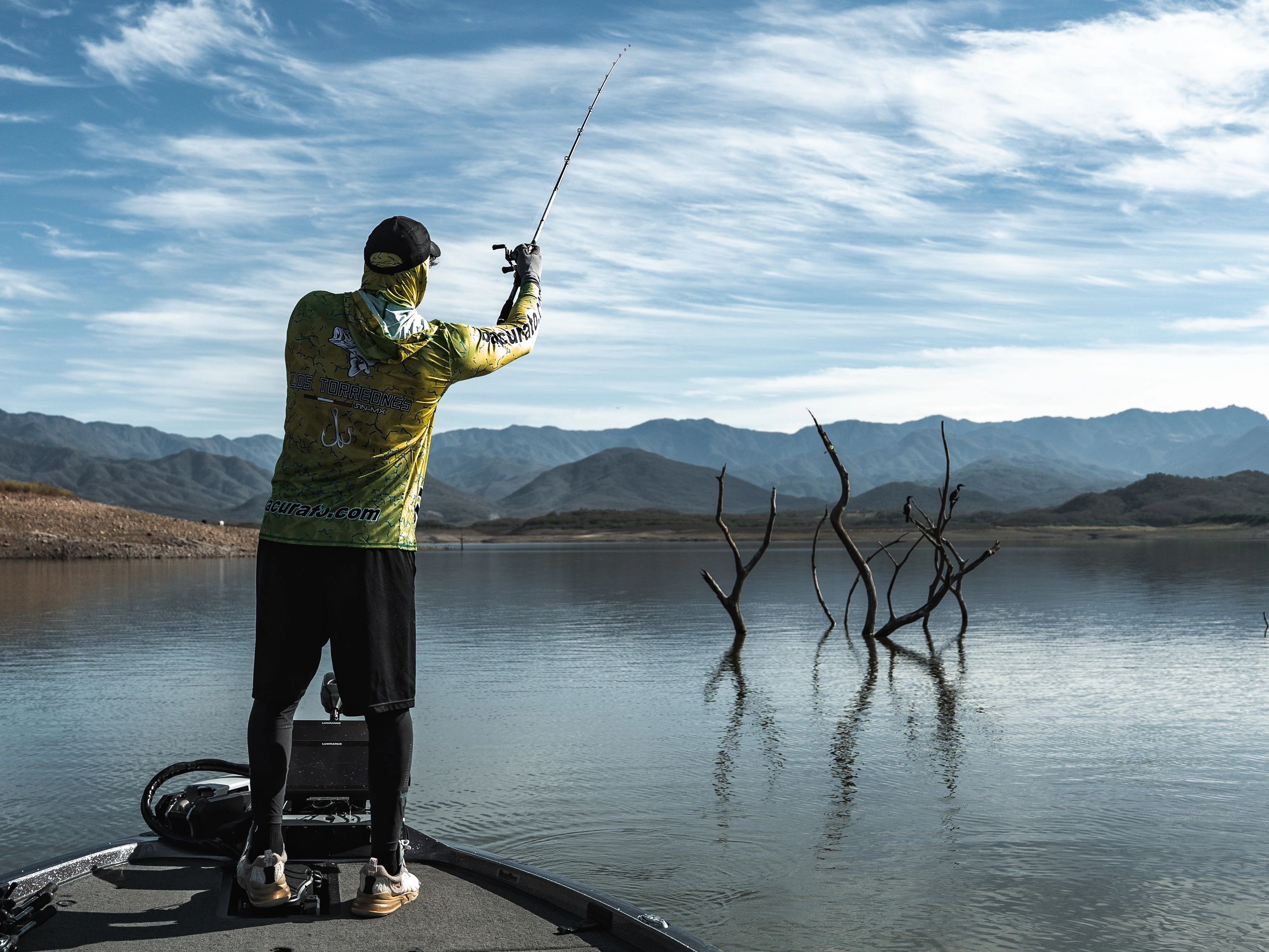 Pescatore in azione su lago montano durante un'uscita outdoor.
