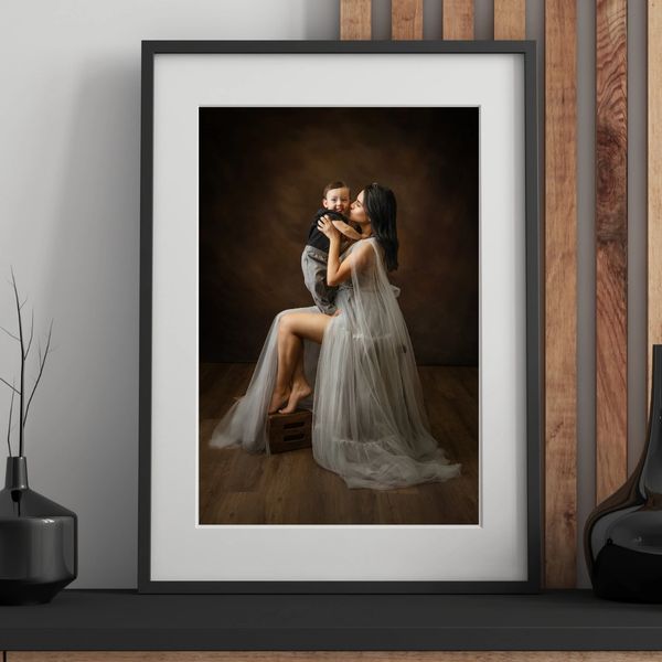Elegant photo of a woman in a flowing dress holding and kissing a baby.