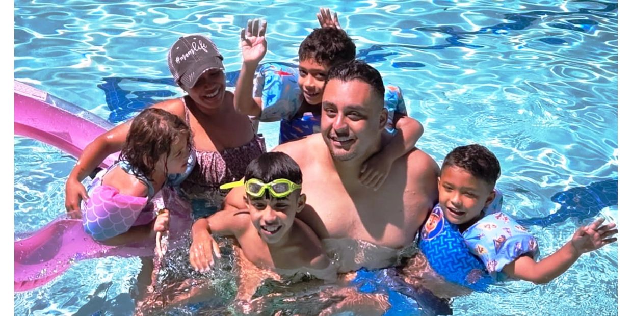 A joyful family enjoying time together in a swimming pool on a sunny day.