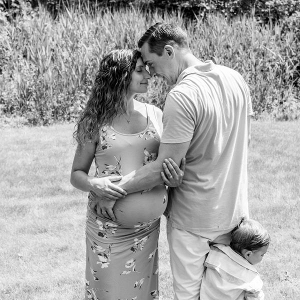 A loving couple with a pregnant woman and a child outdoors.