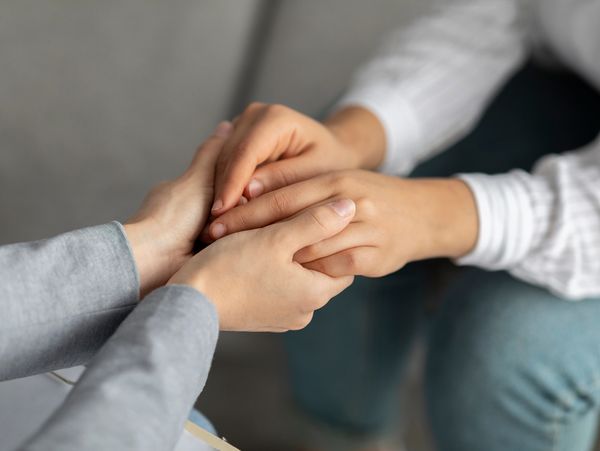 A psychotherapist holding the hands of a patient