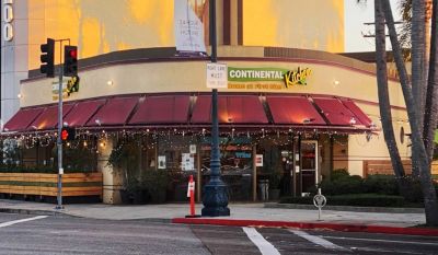 Corner restaurant with red awnings and string lights at sunset.