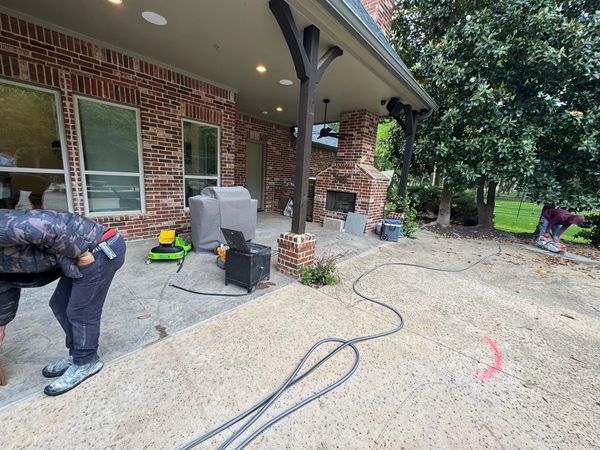 A backyard patio with a brick fireplace and outdoor furniture.