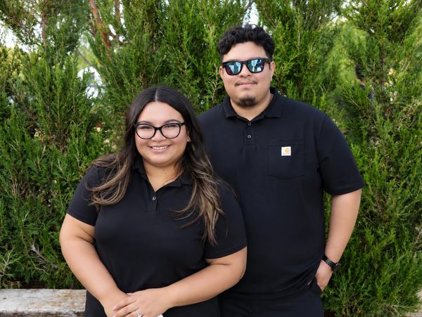 Smiling couple in black shirts outdoors.