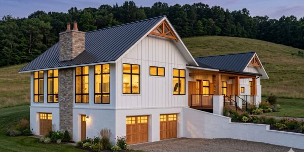 Modern farmhouse with warm interior lighting at dusk.