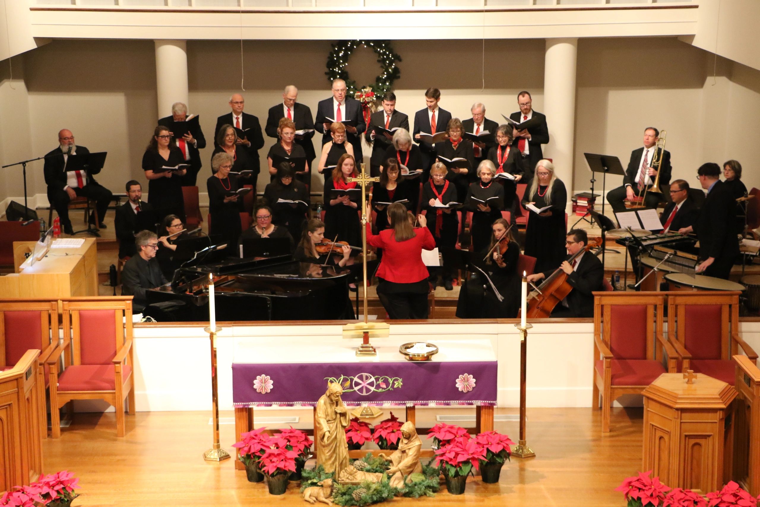 A choir and orchestra perform in a decorated church during Christmas.