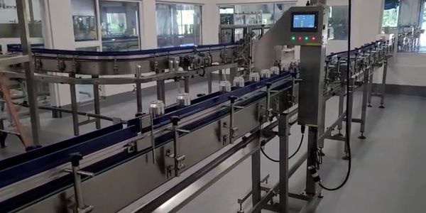 Automated conveyor system transporting cans in a clean factory environment.