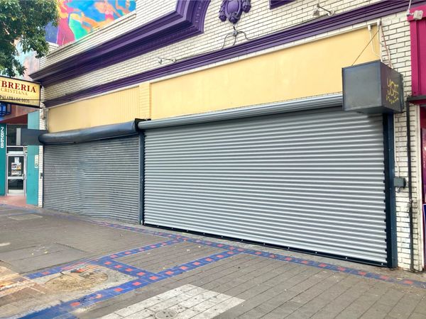 Closed storefronts with metal shutters on a city street.