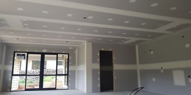Unfinished interior room with drywall installed and taped, awaiting further finishing.
