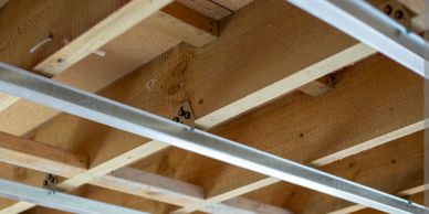 Exposed wooden ceiling beams with metal framing in construction.