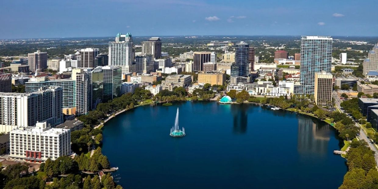 A city skyline with a large lake and fountain in the foreground.