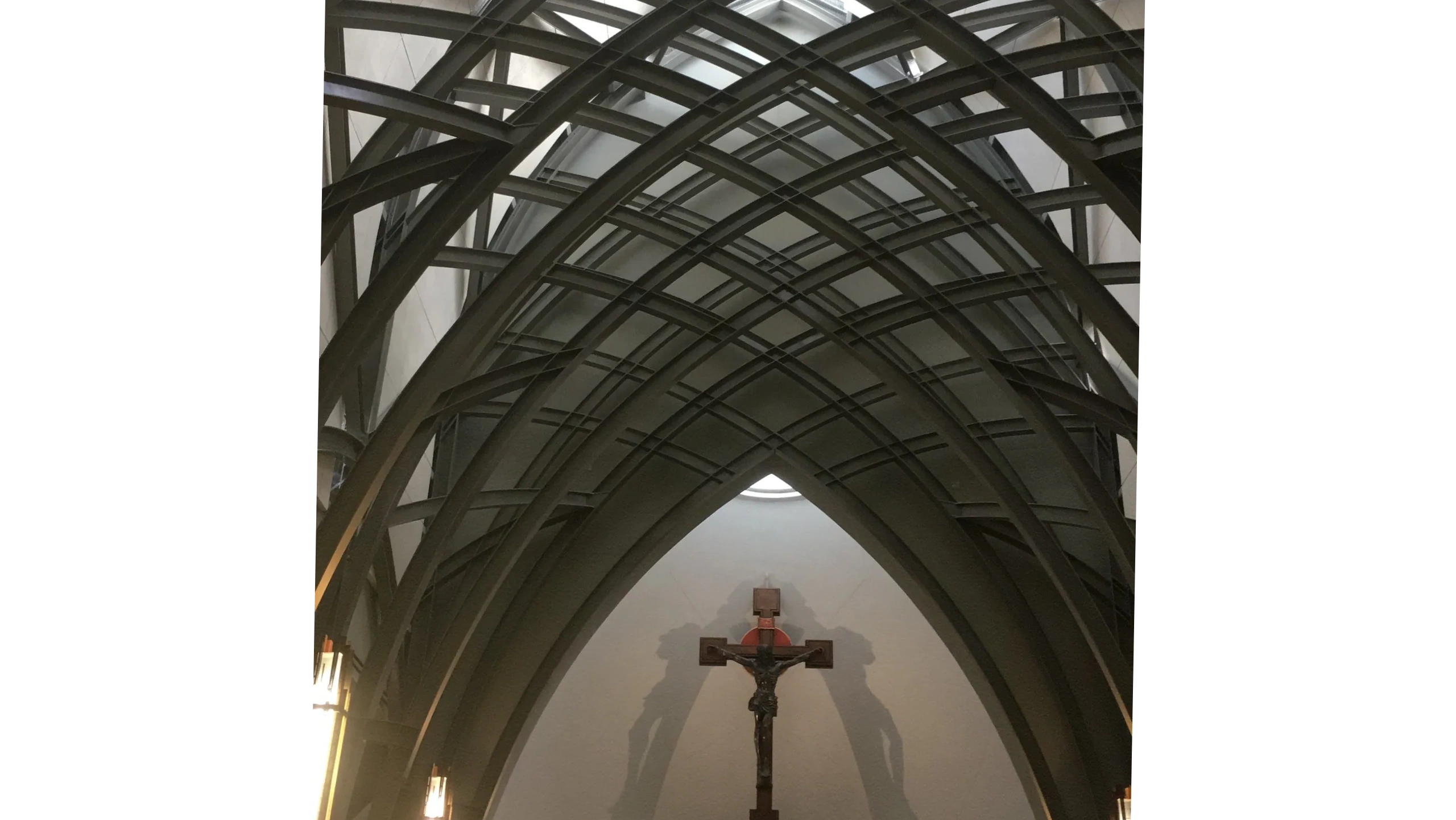 Intricate gothic arches frame a crucifix inside a church.