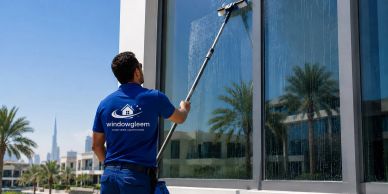 Man cleaning large glass window with squeegee.