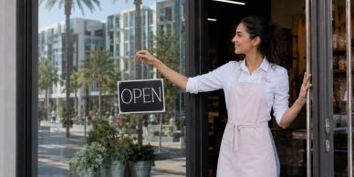 Woman hanging an open sign at a shop entrance.
