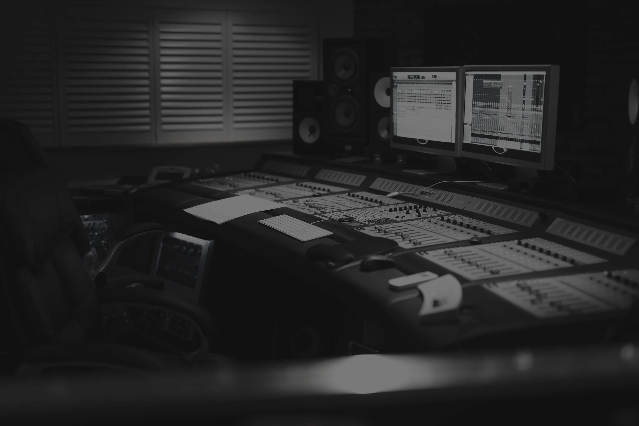 Recording studio with a mixing console and computer screens.
