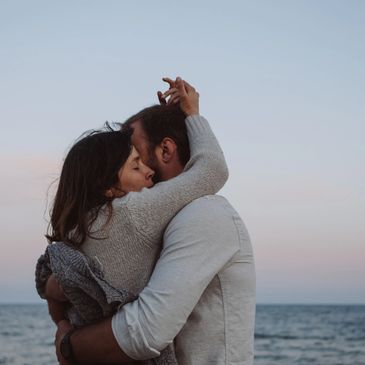 Couple embracing tenderly by the sea at dusk.