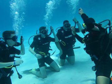 Four scuba divers underwater practicing skills on the ocean floor.