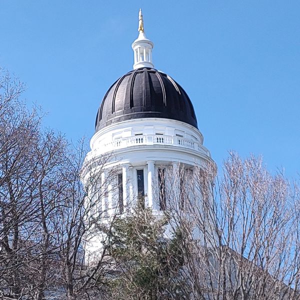White domed building with a statue on top against a clear blue sky.
