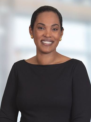 Smiling woman in black top with gold earrings in a bright indoor setting.