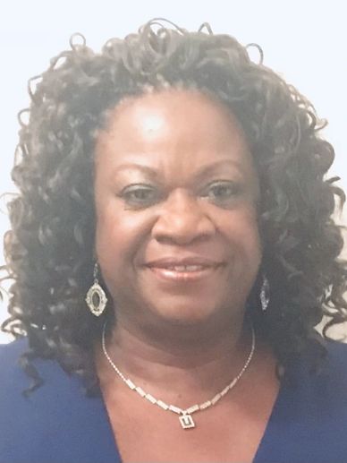 Smiling woman with curly hair wearing earrings and necklace.