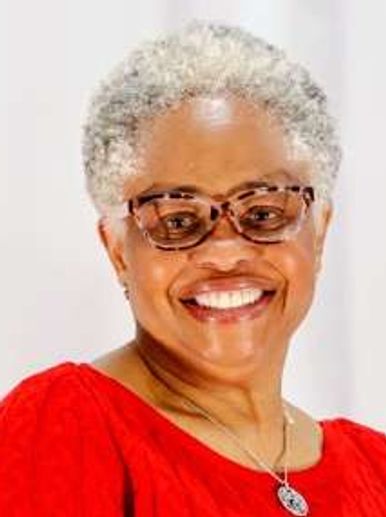 Smiling woman with gray hair and glasses in a red top.