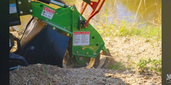 Close-up of a green tiller machine working soil outdoors.