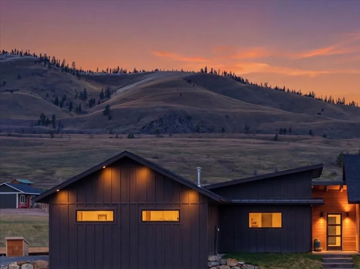 Modern house with warm lights against a mountain sunset.
