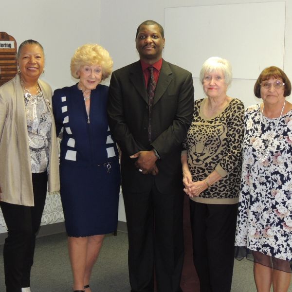 Group photo of five people standing indoors.