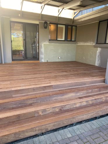 Newly installed wooden deck with steps leading to a covered patio area.