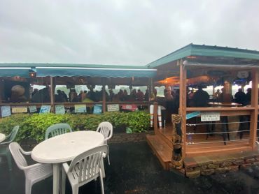 Outdoor dining area with covered seating and plastic chairs on a rainy day.