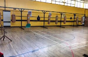 Empty gym with hanging punching bags and wooden floor.