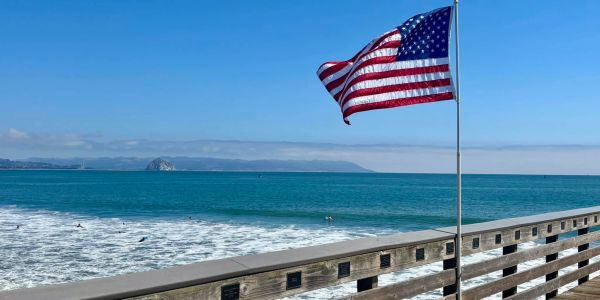 American flag waving on a pier by the ocean.