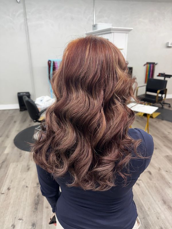 Voluminous wavy hair with a rich auburn shade styled elegantly.