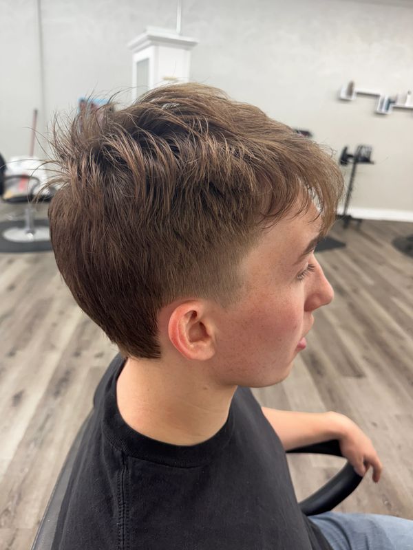 Side view of a young man with a fresh, textured haircut in a modern salon.