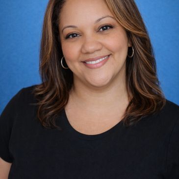 Smiling woman with hoop earrings against a blue background.
