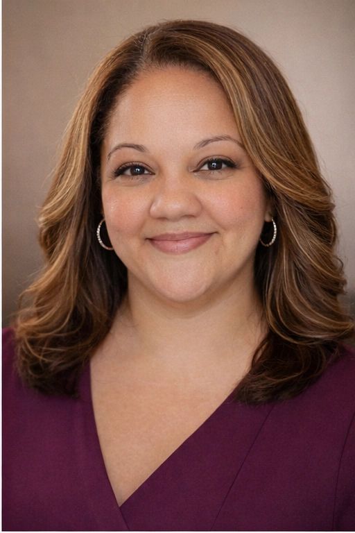 Smiling woman with wavy hair in a purple top and hoop earrings.