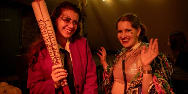 Two women in colorful costumes smiling at a party.