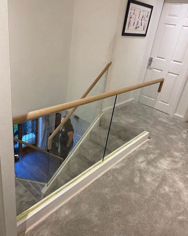 A white with Oak mop stick handrails and frameless glass installed in Kings Langley,  Hertfordshire.