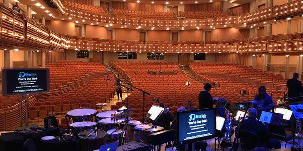 Empty concert hall stage with musical instruments and monitors.