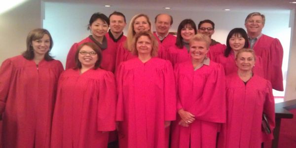 A group of people in red choir robes posing indoors.
