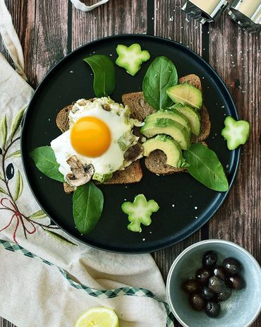 top view for sunny side up egg toast avocado with olives on a wooden background