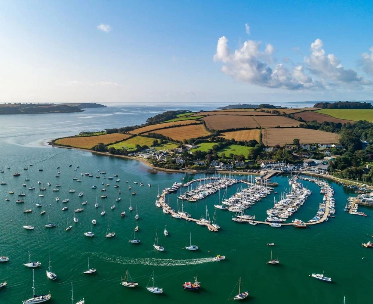 Mylor harbour taken by a drone looking out to sea over the hills into Falmouth bay on a beautiful su