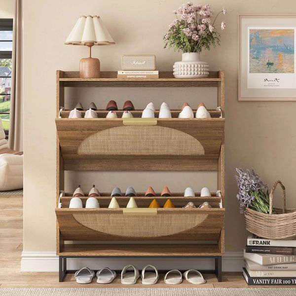 Wooden shoe rack with two shelves filled with shoes, a lamp, and a vase on top.