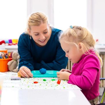 A woman and a little girl are crafting together at a table.