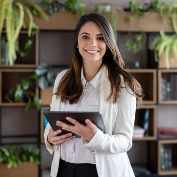 Smiling professional woman holding a tablet in a modern office with plants.