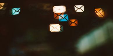 Blurry glowing envelope icons floating against a dark background.