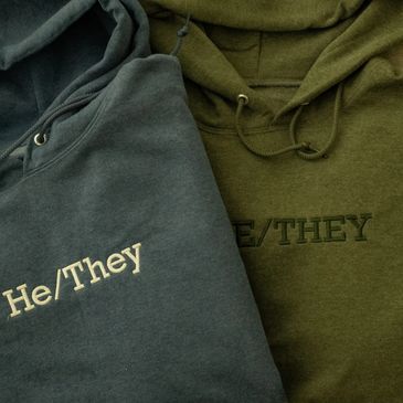 Three of our pronoun sweatshirts in blue, green, and a heather grey featuring various pronouns